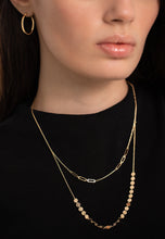 Load image into Gallery viewer, A person wearing a black outfit and gold jewelry, including a necklace with multiple charms and a chain bracelet.