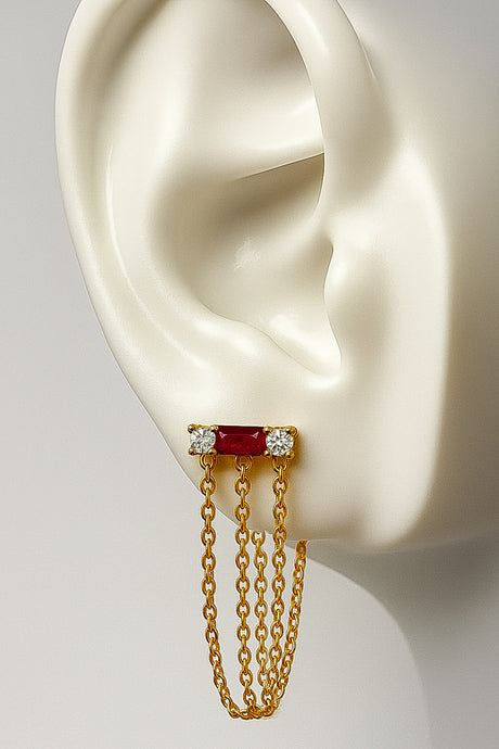 Gold earring with red gemstone and chains on a white ear model