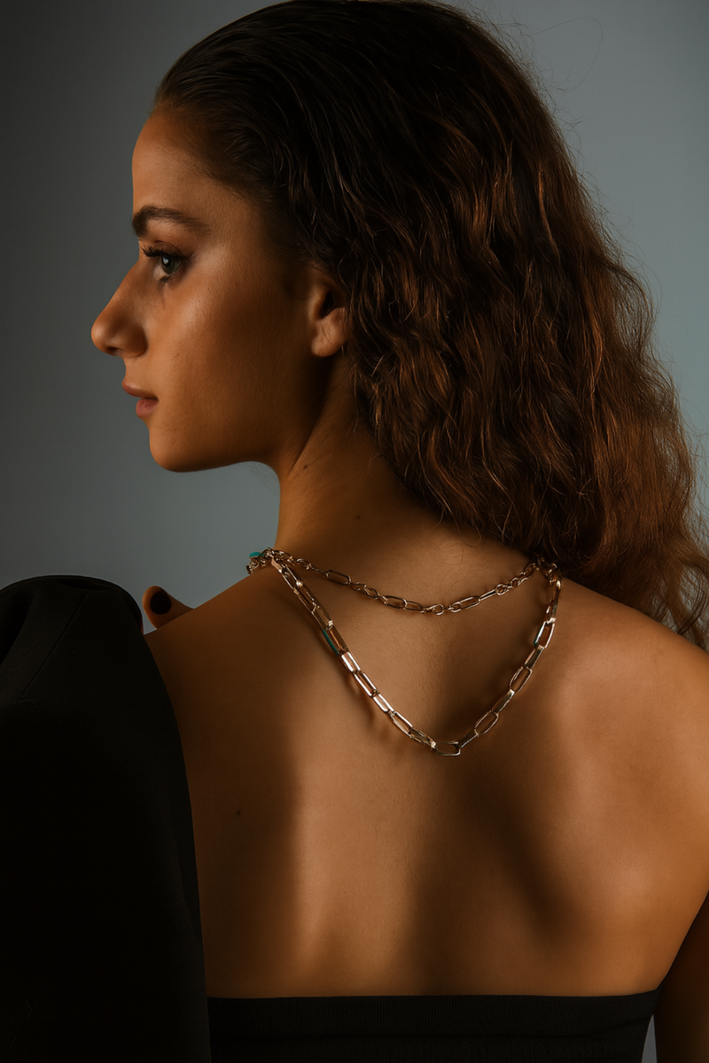 Woman wearing a chain necklace with a neutral background