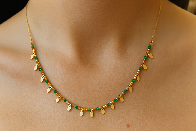 Gold necklace with green beads on a person's neck