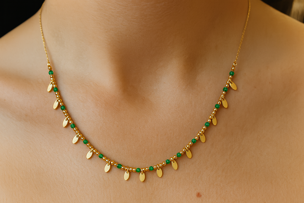 Gold necklace with green beads on a person's neck