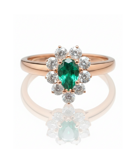Rose gold ring with emerald and diamond accents on a white background