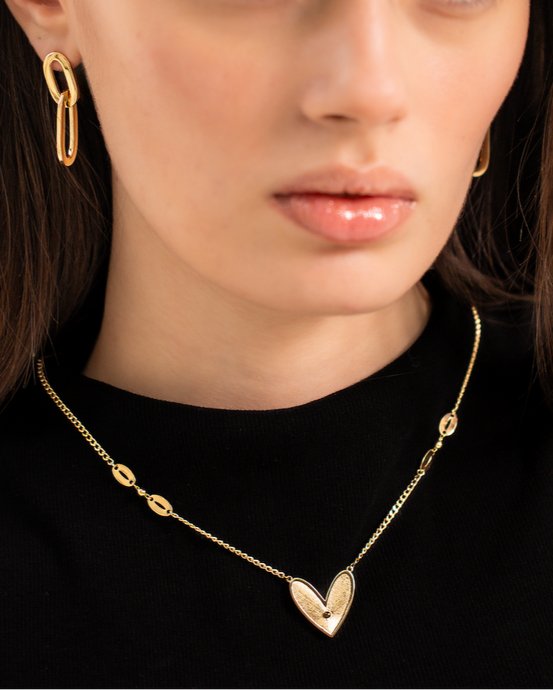 Woman wearing a gold necklace and earrings on a plain background