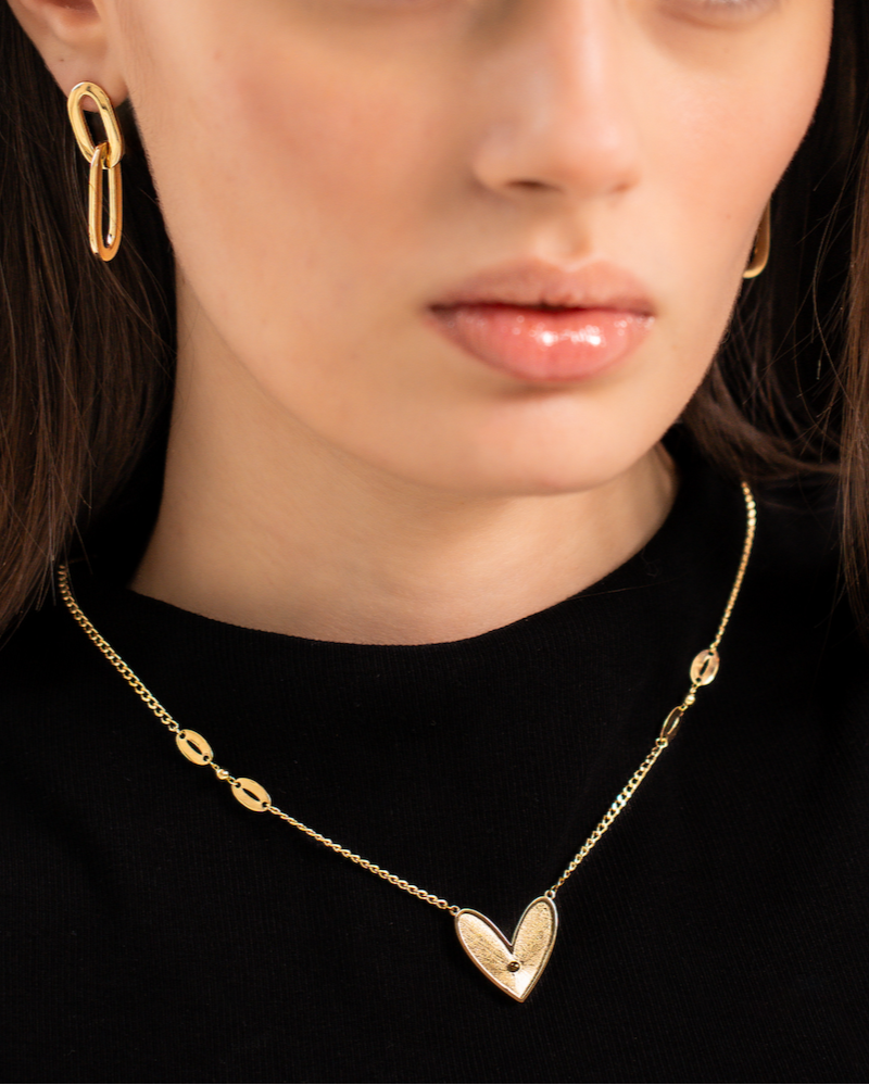 Woman wearing a gold necklace and earrings on a plain background