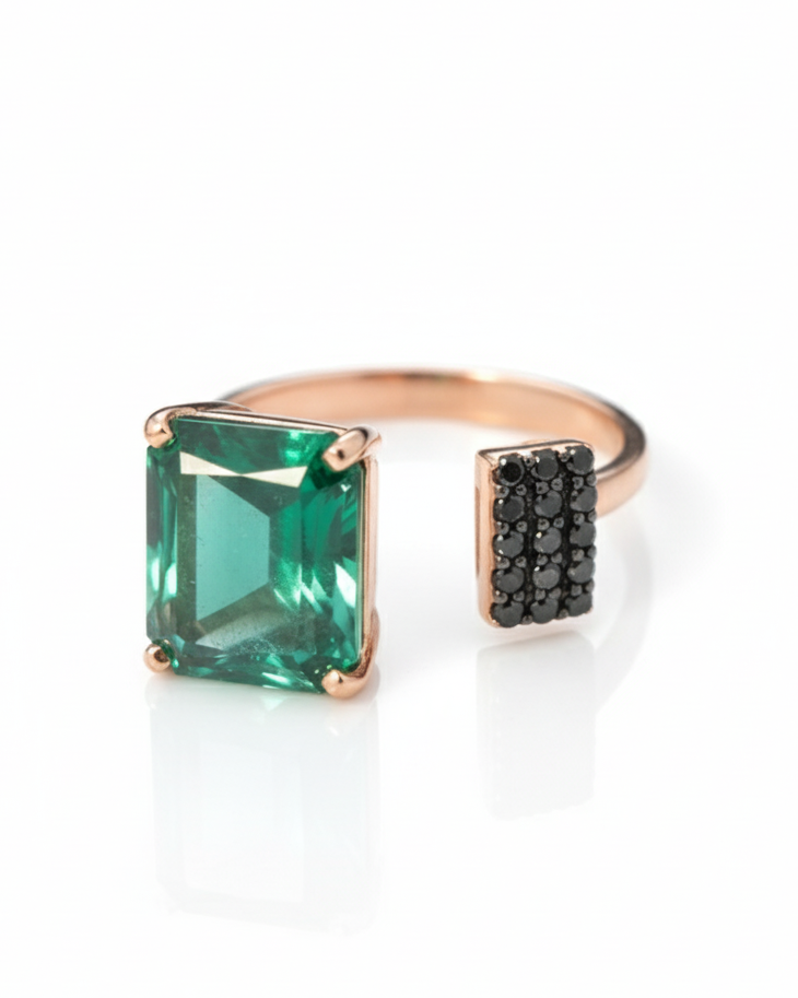 Ring with green gemstone and black diamond accents on a white background