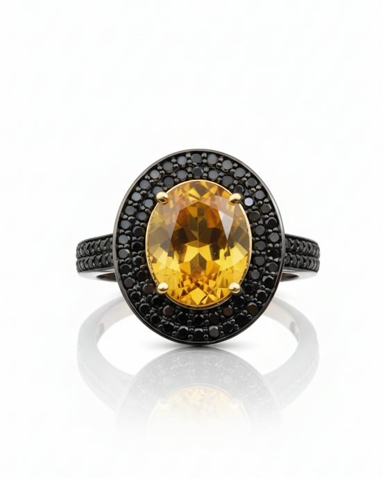 Ring with a yellow gemstone and black accents on a white background